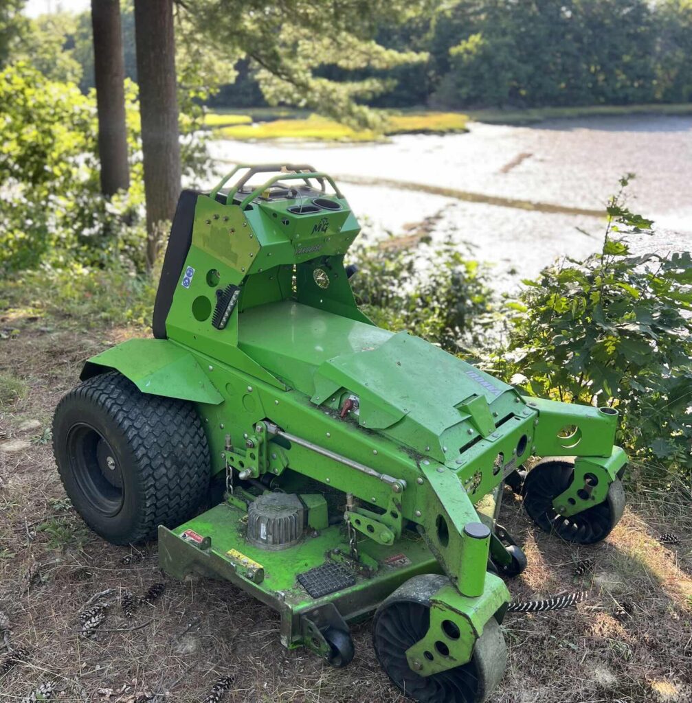 Mean Green mower on lawn overlooking salt marsh during landscaping service in Kittery Maine