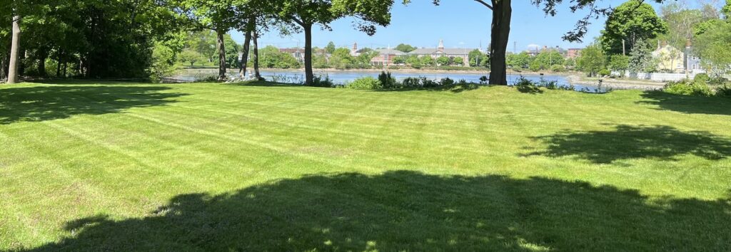 Freshly striped lawn overlooking the water during landscape maintenance service in New Castle NH