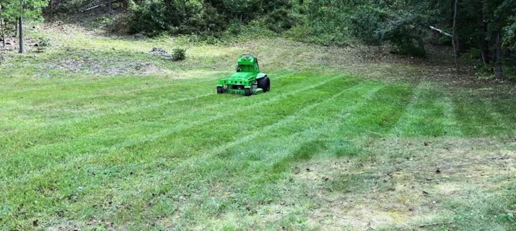 Mean Green electric mower creating striped lawn during lawn landscaping service in Portsmouth NH