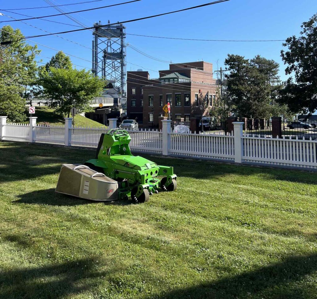 Electric lawn mower creating striped lawn on downtown Portsmouth NH waterfront