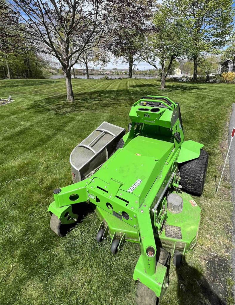 Electric lawn mower creating striped lawn overlooking Portsmouth NH waterfront