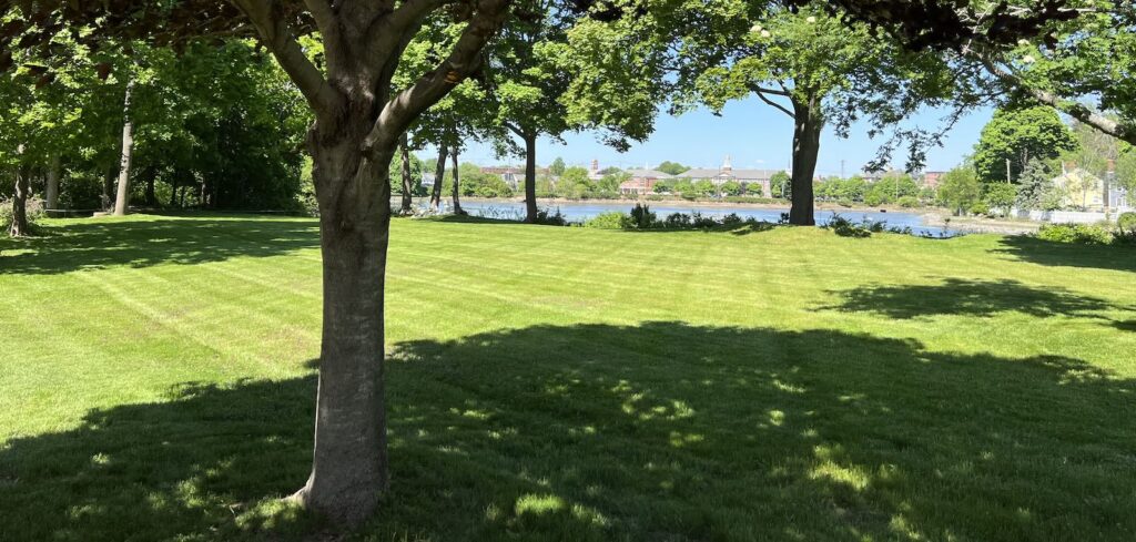 Professionally striped lawn overlooking Mill Pond during landscaping service in Portsmouth NH